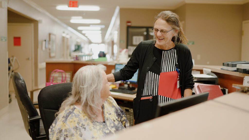 A woman smiles at a skilled nursing facility staff worker