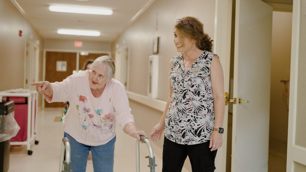 A nurse and a long term care resident walking down a hallway
